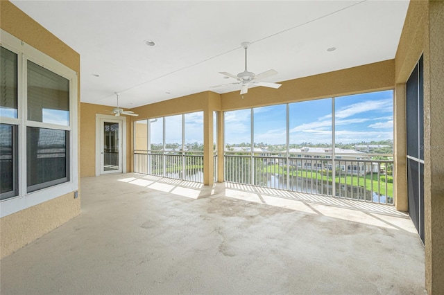 unfurnished sunroom featuring ceiling fan and a water view