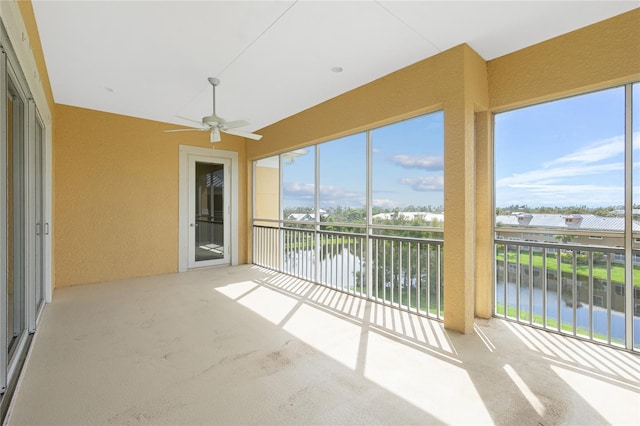 unfurnished sunroom featuring a water view and ceiling fan