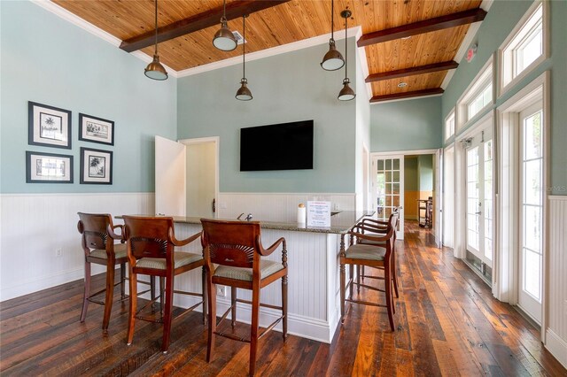 kitchen featuring a breakfast bar, decorative light fixtures, wood ceiling, and french doors