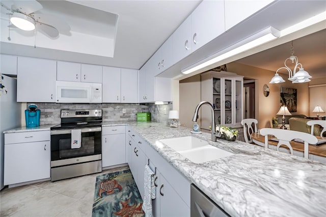 kitchen with ceiling fan with notable chandelier, white appliances, sink, tasteful backsplash, and pendant lighting