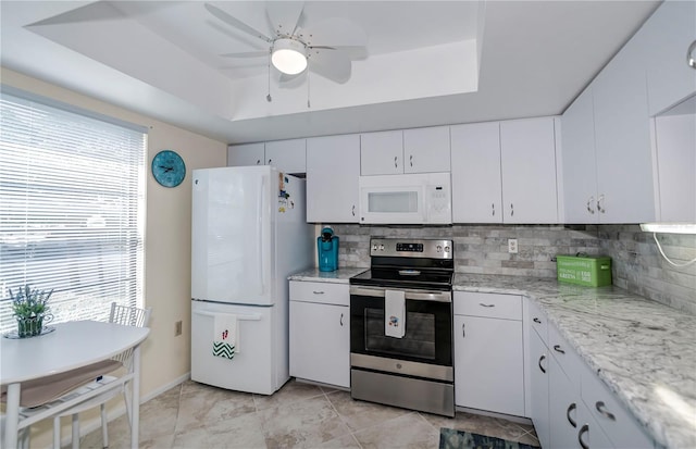 kitchen featuring white appliances, ceiling fan, white cabinets, and a raised ceiling