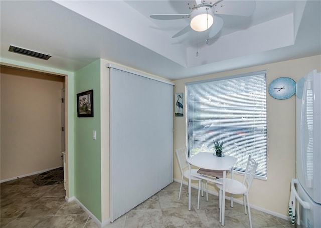 tiled dining room with a tray ceiling and ceiling fan