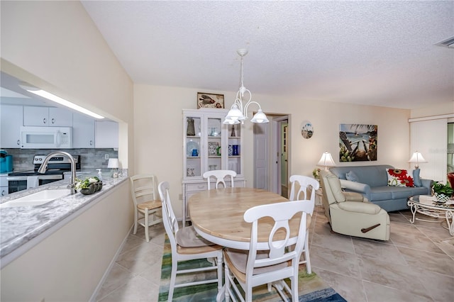 dining area with an inviting chandelier, a textured ceiling, light tile flooring, and sink