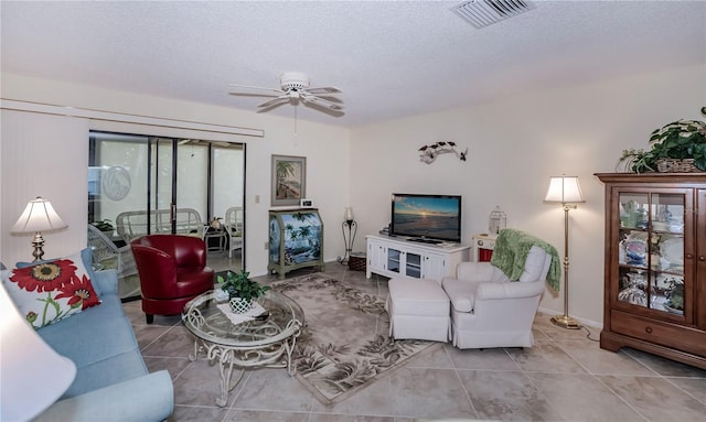 living room featuring a textured ceiling, ceiling fan, and light tile floors