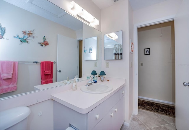 bathroom featuring toilet, vanity, and tile flooring