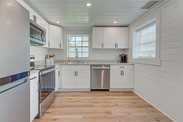 kitchen featuring sink, white cabinets, light hardwood / wood-style flooring, stainless steel appliances, and light stone countertops