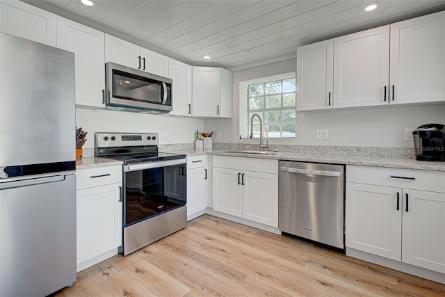 kitchen with white cabinetry, sink, light hardwood / wood-style flooring, stainless steel appliances, and light stone counters