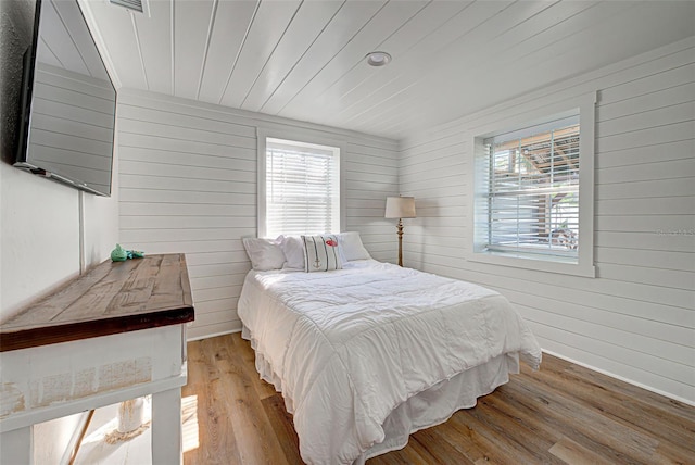 bedroom with wood-type flooring and wood walls