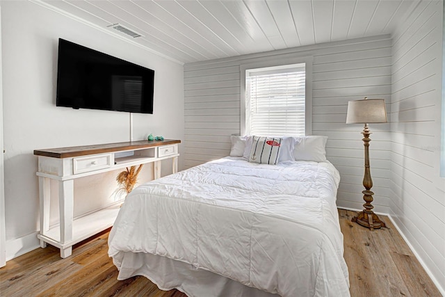 bedroom with wooden walls and light hardwood / wood-style flooring