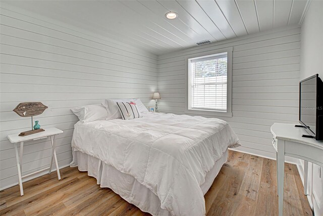 bedroom with wood walls and light wood-type flooring