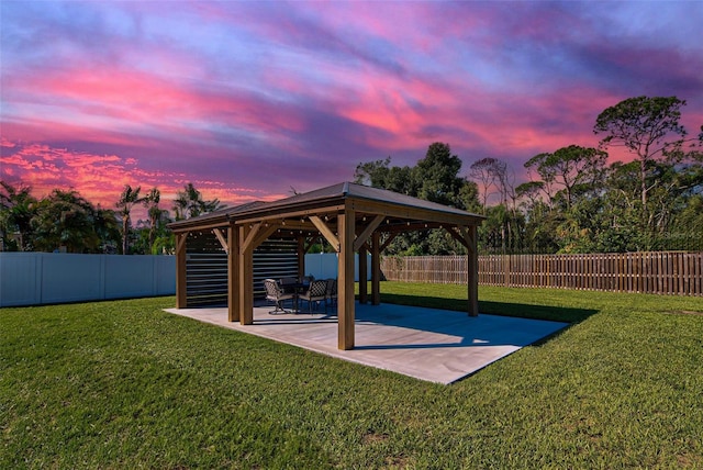 yard at dusk featuring a gazebo and a patio