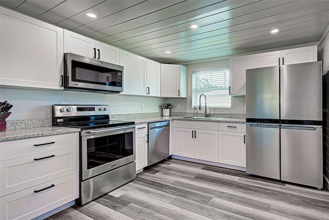 kitchen featuring white cabinets, appliances with stainless steel finishes, light hardwood / wood-style floors, and sink