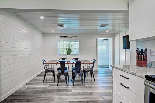 dining space featuring wooden walls and hardwood / wood-style flooring