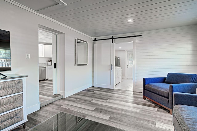 living room with a barn door, light wood-type flooring, and washer / dryer