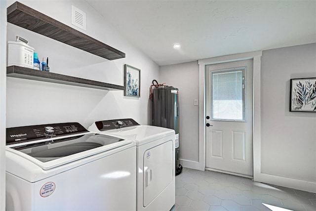 clothes washing area with electric water heater, light tile floors, and washer and clothes dryer