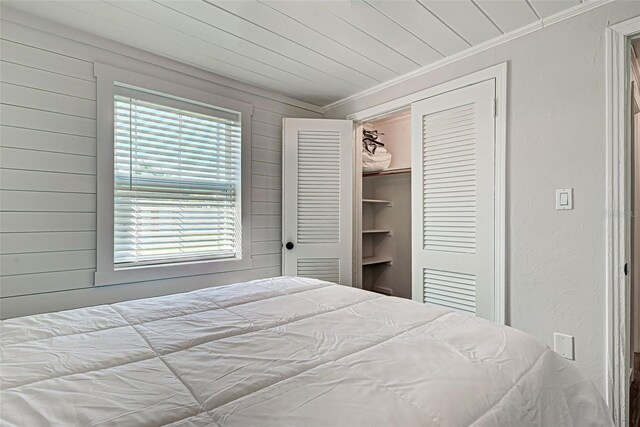 bedroom with a spacious closet, a closet, ornamental molding, and multiple windows