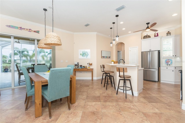 tiled dining room with plenty of natural light, ceiling fan, and ornamental molding