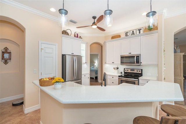 kitchen with ceiling fan, white cabinets, appliances with stainless steel finishes, a breakfast bar, and decorative light fixtures