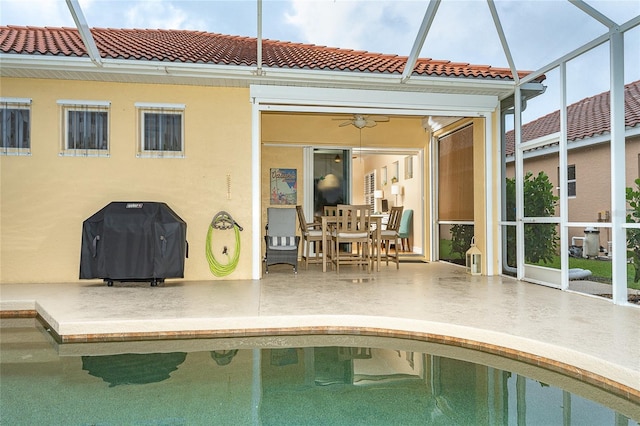 view of swimming pool featuring a grill, ceiling fan, glass enclosure, and a patio