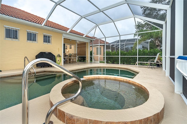 view of pool featuring an in ground hot tub, glass enclosure, and a patio area