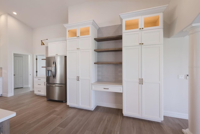 kitchen featuring stainless steel fridge, light hardwood / wood-style flooring, white cabinetry, and ornate columns