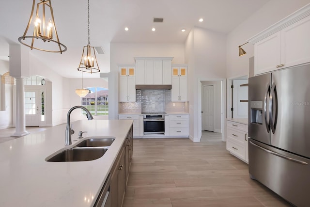 kitchen with decorative light fixtures, stainless steel appliances, white cabinetry, and sink