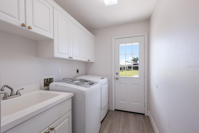 laundry area with washing machine and clothes dryer, light hardwood / wood-style flooring, cabinets, and sink