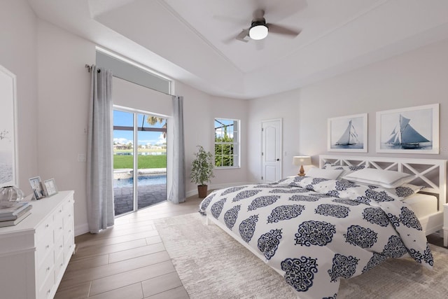 bedroom with access to outside, a raised ceiling, and ceiling fan