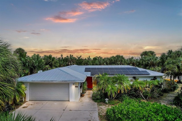 ranch-style home with solar panels and a garage