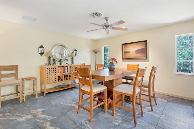 dining area with dark tile floors and ceiling fan