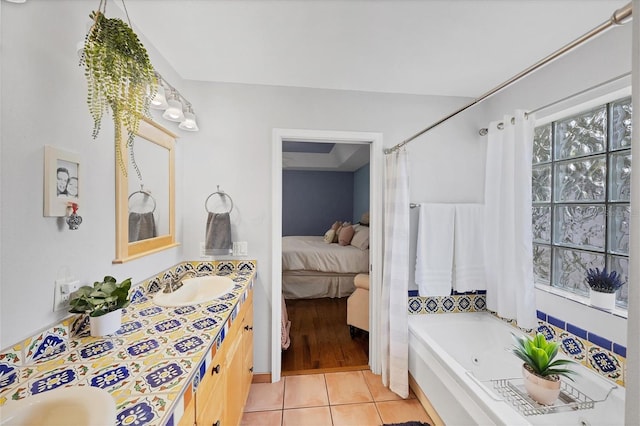 full bath with a garden tub, double vanity, connected bathroom, a sink, and tile patterned flooring