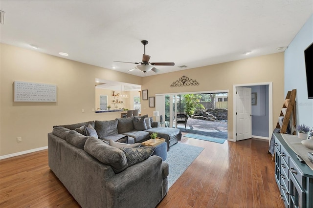 living room with ceiling fan, wood finished floors, visible vents, and baseboards