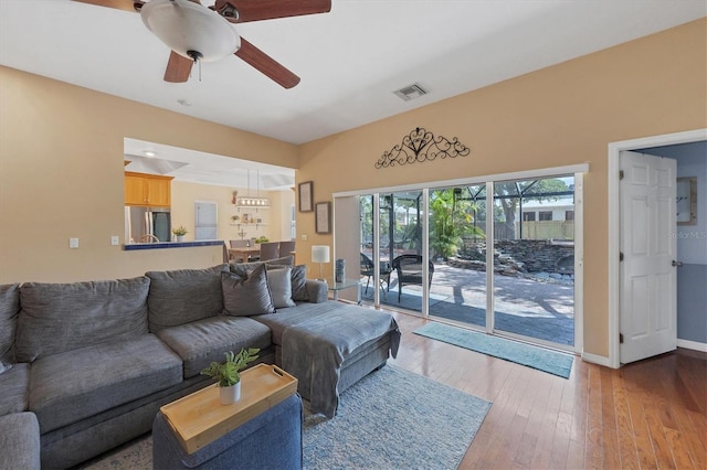 living area with a ceiling fan, baseboards, visible vents, and light wood finished floors