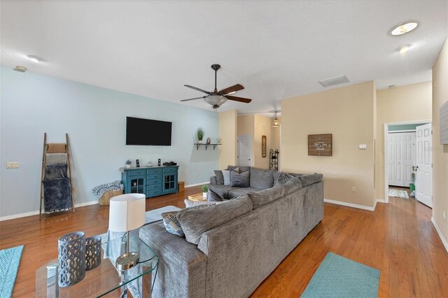 living area with visible vents, ceiling fan, light wood-style flooring, and baseboards