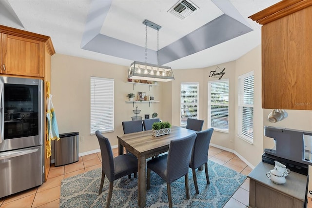 dining room featuring a raised ceiling, visible vents, baseboards, and light tile patterned floors