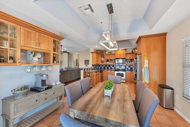 dining area with baseboards, visible vents, a raised ceiling, and light tile patterned flooring