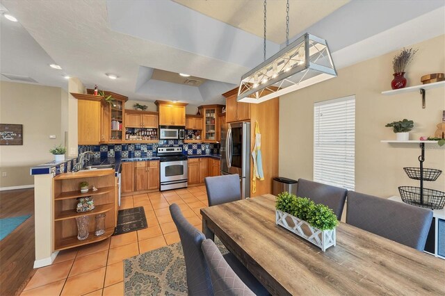 dining area with visible vents, baseboards, a tray ceiling, and light tile patterned flooring