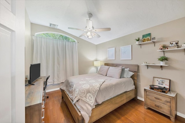 bedroom with visible vents, baseboards, a ceiling fan, lofted ceiling, and wood finished floors