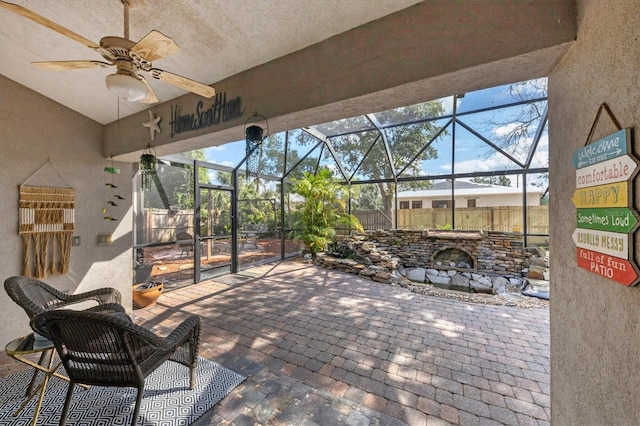 view of patio / terrace featuring glass enclosure, ceiling fan, and fence