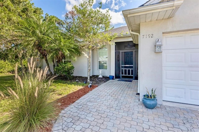 view of exterior entry featuring a garage and stucco siding