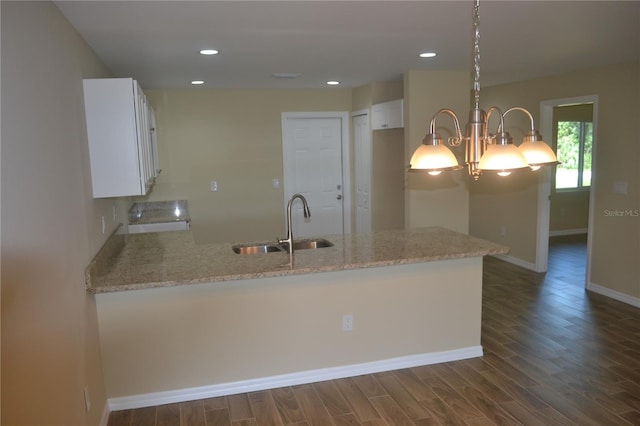 kitchen featuring white cabinets, hanging light fixtures, dark hardwood / wood-style flooring, and light stone counters