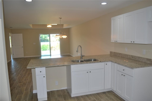 kitchen with white cabinets, an inviting chandelier, kitchen peninsula, and sink