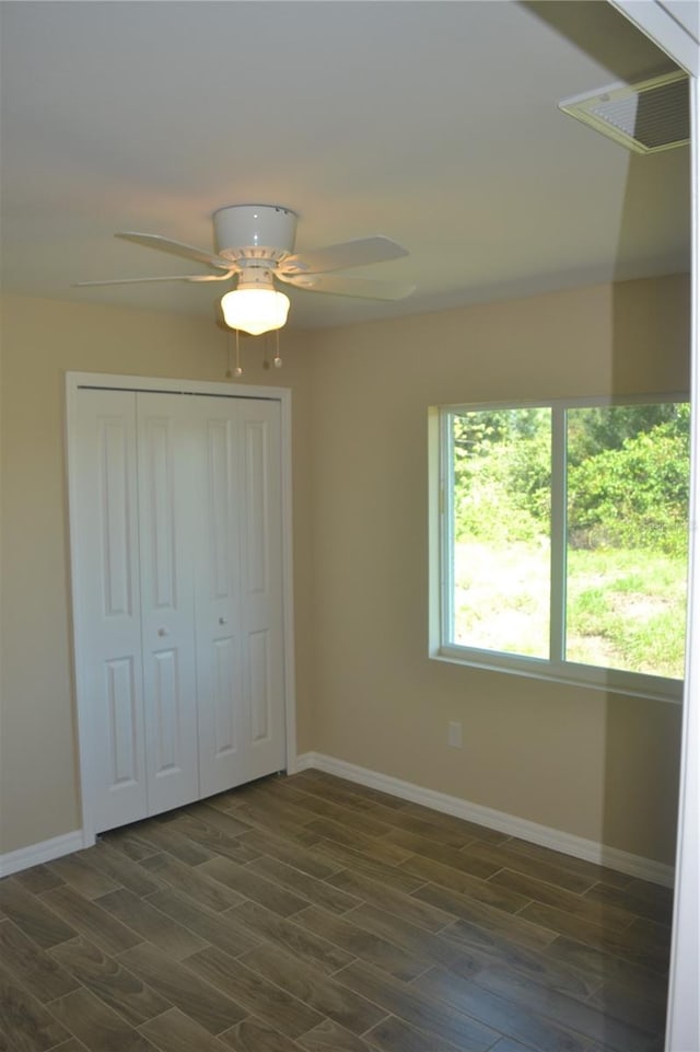 unfurnished bedroom featuring a closet, ceiling fan, and dark wood-type flooring