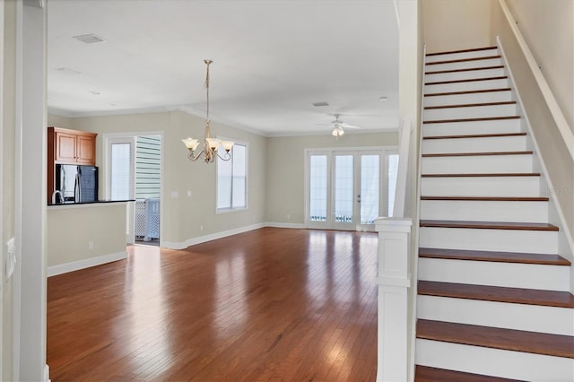 stairway featuring dark hardwood / wood-style floors, ceiling fan with notable chandelier, and ornamental molding