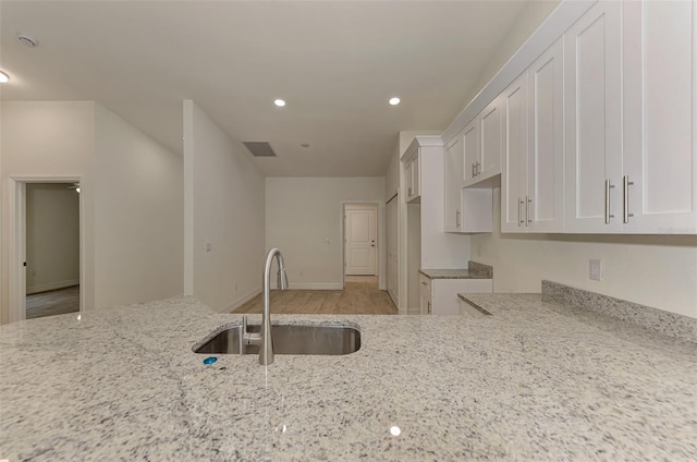 kitchen featuring white cabinets, light hardwood / wood-style floors, light stone counters, and sink