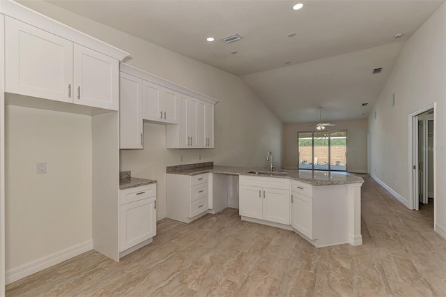 kitchen with kitchen peninsula, ceiling fan, sink, white cabinets, and vaulted ceiling