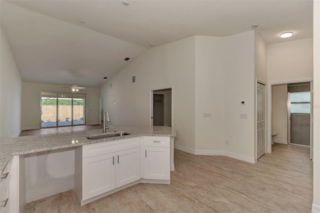 kitchen featuring light tile floors, ceiling fan, sink, white cabinets, and light stone counters