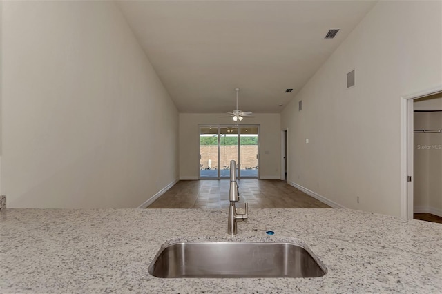 kitchen featuring light stone countertops, ceiling fan, and sink