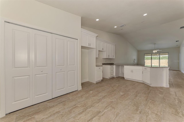 kitchen featuring kitchen peninsula, ceiling fan, sink, vaulted ceiling, and white cabinetry