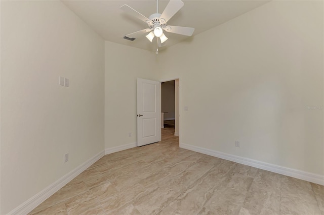 tiled spare room featuring ceiling fan and a towering ceiling